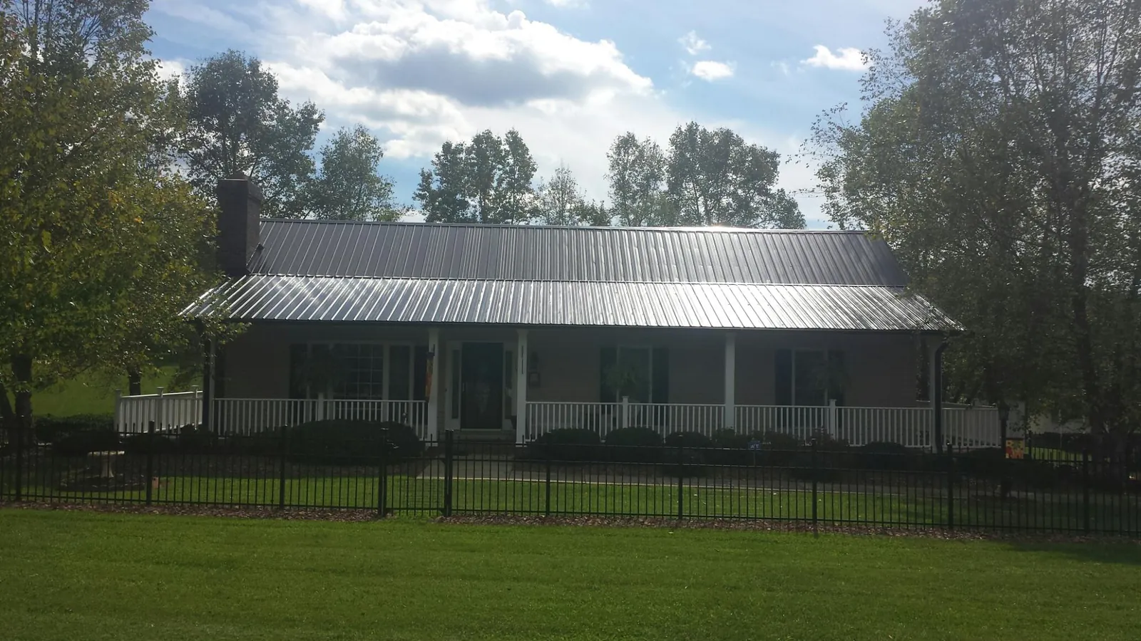 Gray metal roof on a brick ranch with a full width front porch — Gutter Guard Installation work by our crew in Carbondale