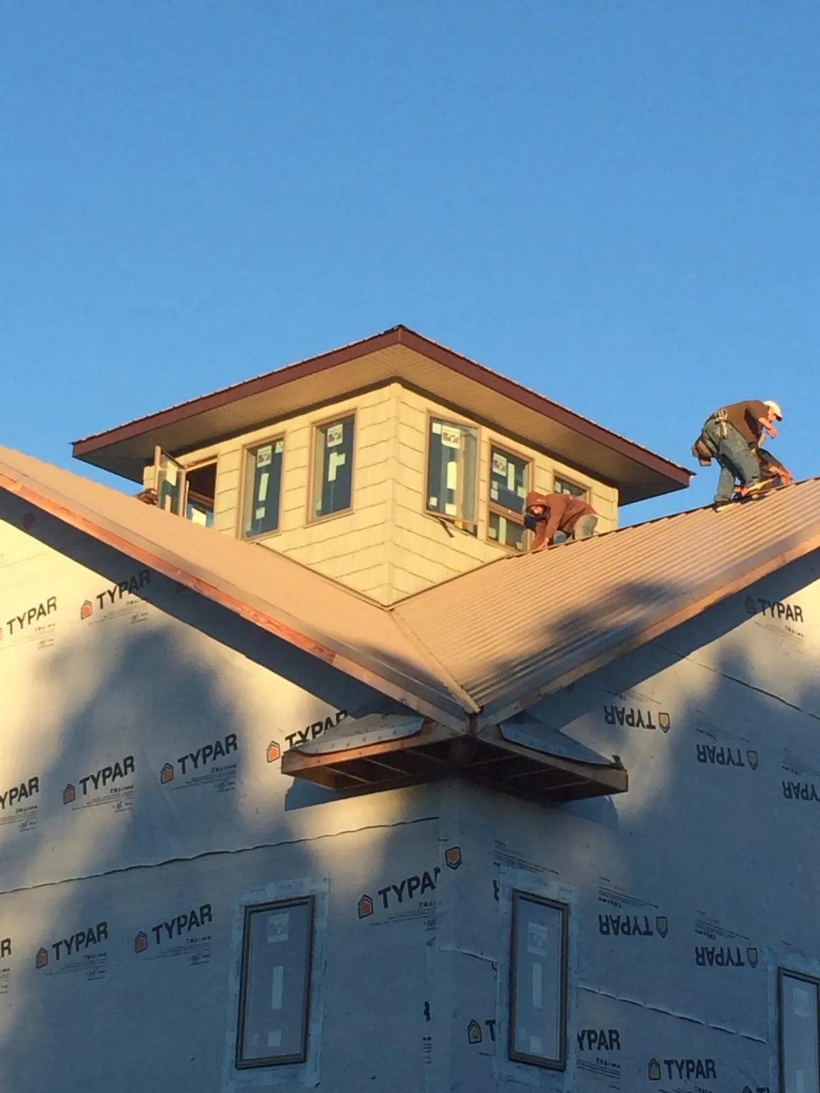 Roofers working around a rooftop cupola on a new metal roof at sunset — Roof Waterproofing in Carbondale by Roofing Brothers